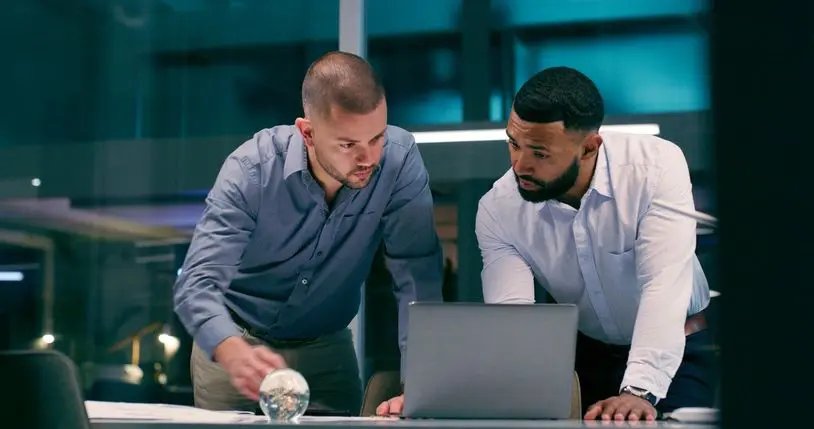 Two men collaborating over a laptop